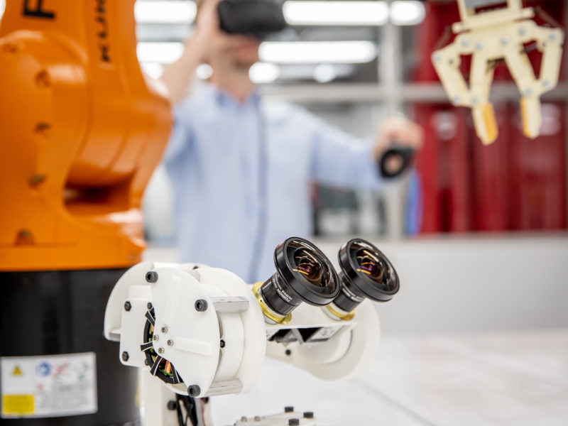 Crane machinery with student using a VR headset in background.