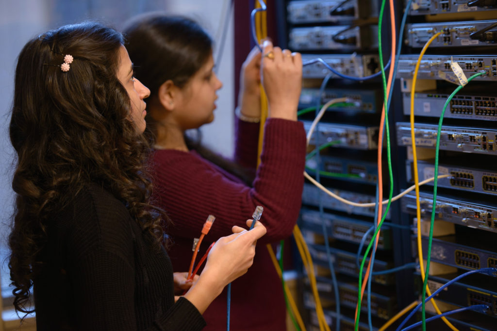 Two young women working on connecting the servers with wires.