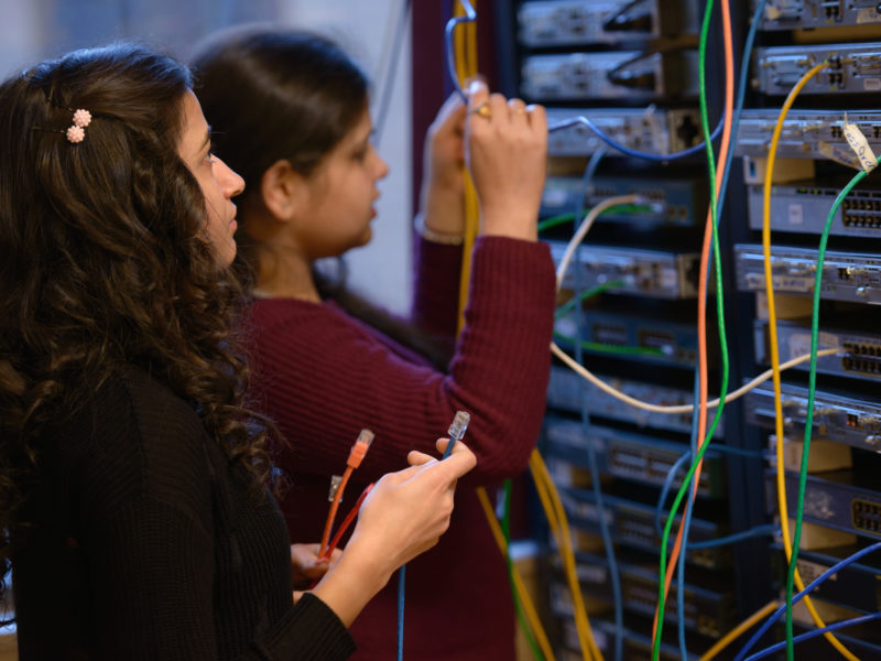Two young women working on connecting the servers with wires.