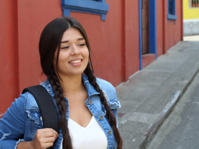 Young student wearing a bagpack smiling.