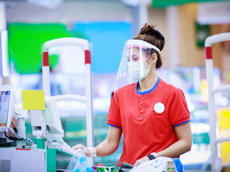 Grocery store cashier wearing a medical mask and face shield.