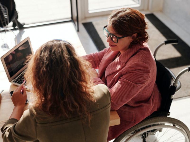 Two woman sitting at a discuss reviewing work on a laptop