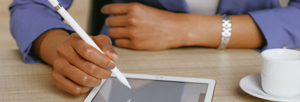 hand holding a stylus and writing on a tablet