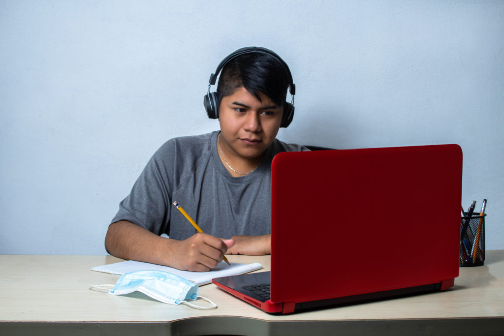 Teenage boy with headphones in front of a laptop