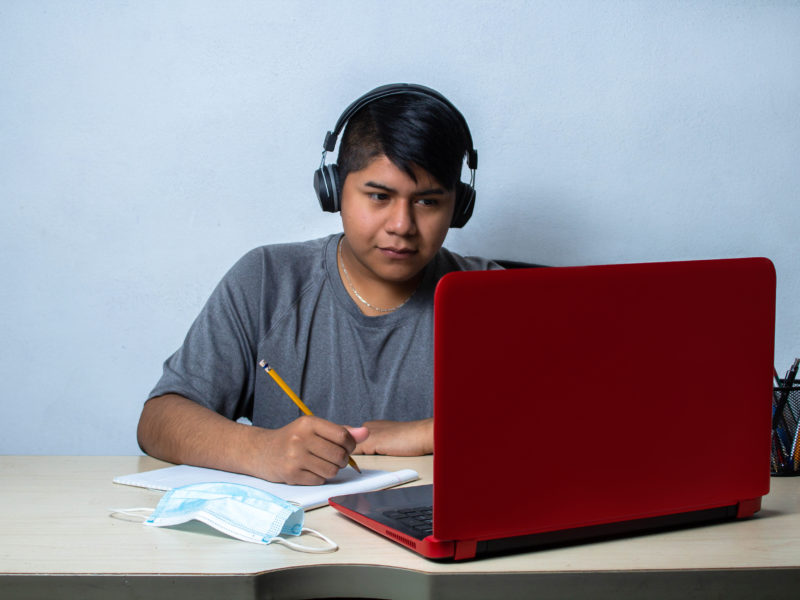 Teenage boy with headphones in front of a laptop
