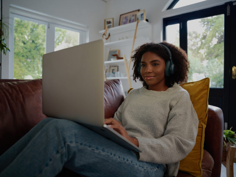 Young person sitting on couch wearing large headphones