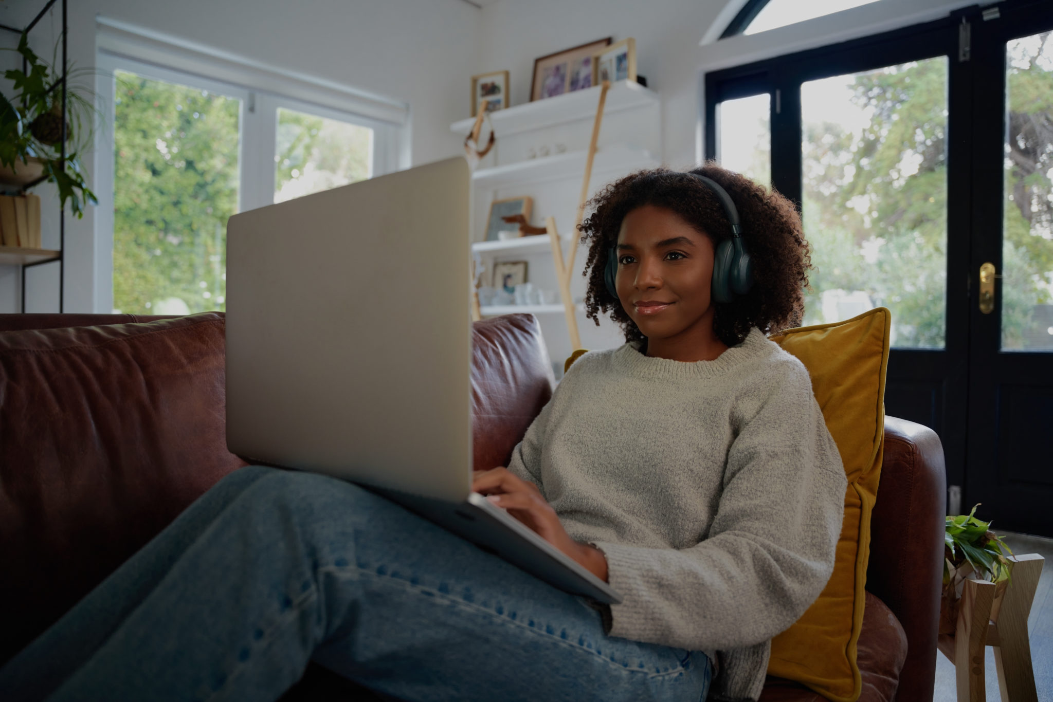 Young person sitting on couch wearing large headphones