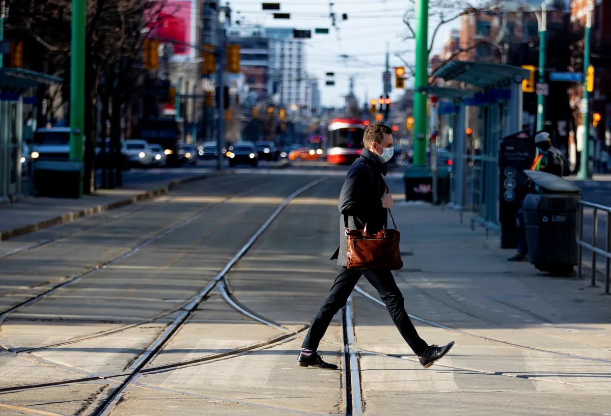 A man walks with a face mask on in Toronto, March 11, 2021.