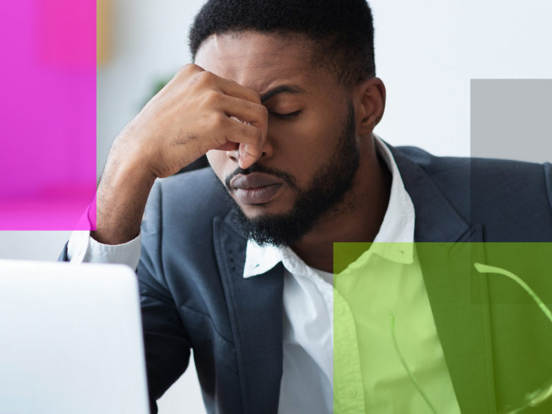 Man with furrowed brows and had massaging bridge of his nose while in front of an opened laptop