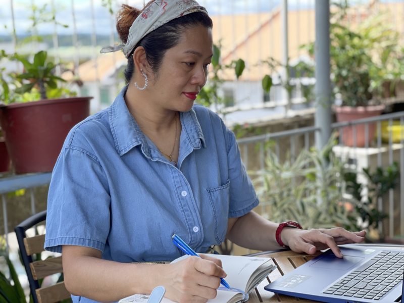 person using a laptop and writing in a notebook