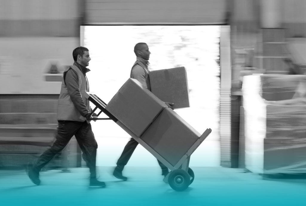 Two workers moving a large cardboard box each on a dolly