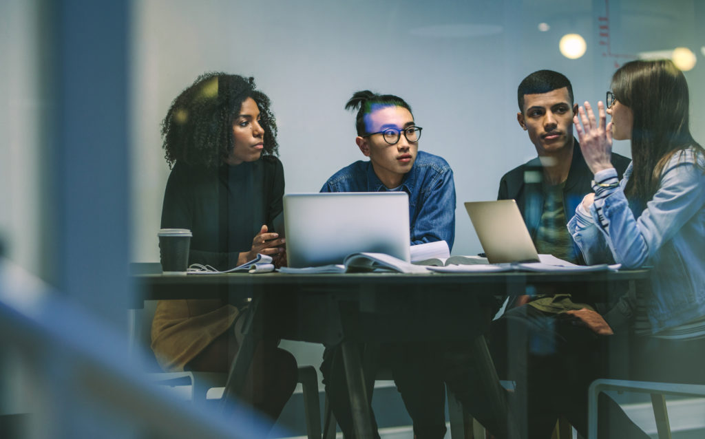diverse workforce sitting around a table with computers