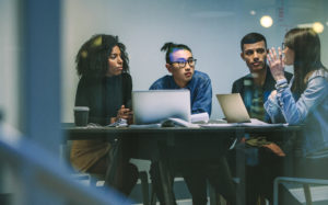 diverse workforce sitting around a table with computers