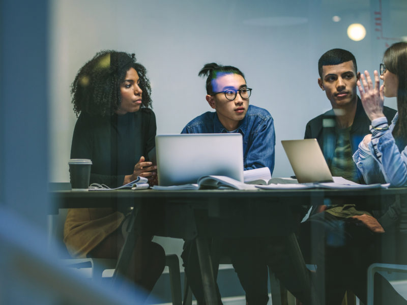 diverse workforce sitting around a table with computers