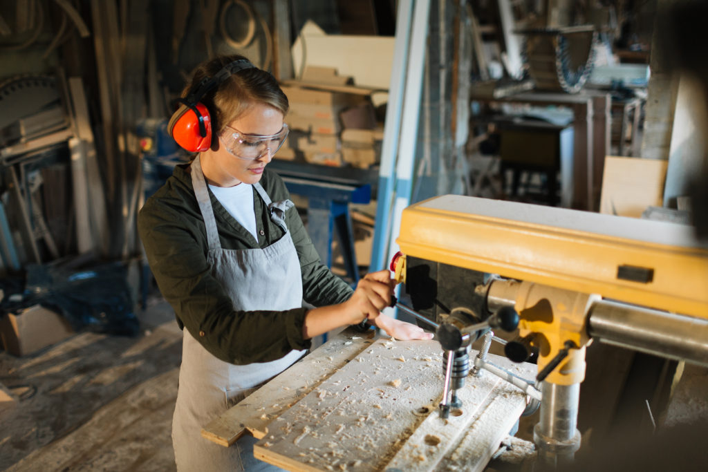 Young woman woodworking by drill-machine
