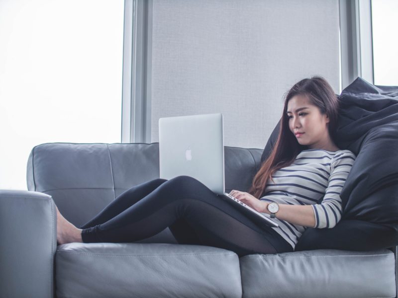 woman relaxes on couch with a laptop