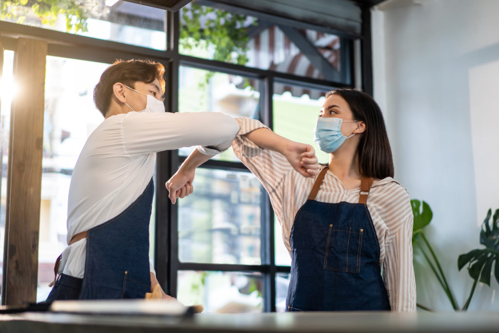 waiter worker greeting waitress girl by elbow bump in restaurant.