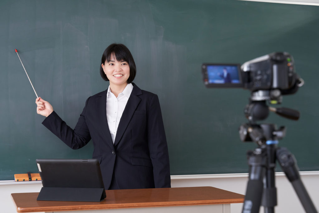 A Japanese female teacher filming an online class in her classroom