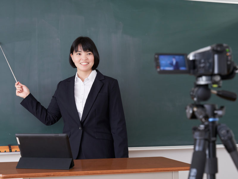 A Japanese female teacher filming an online class in her classroom