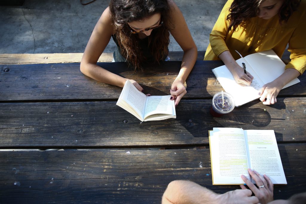 people gathering around a table talking and reading