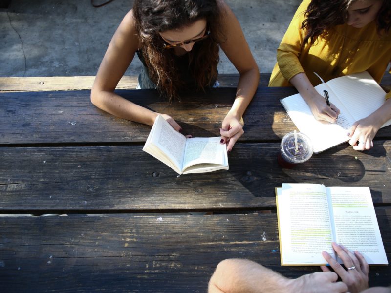 people gathering around a table talking and reading