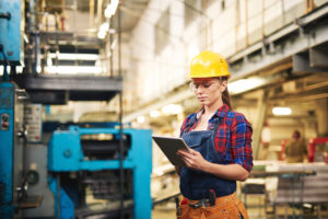 Woman in protective clothing using touchpad in factory