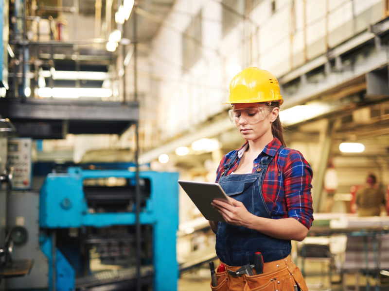 Woman in protective clothing using touchpad in factory