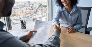 ceo holding employment contract job offer hiring welcoming female African American newcomer worker manager shaking hands in contemporary office. Human resources concept.