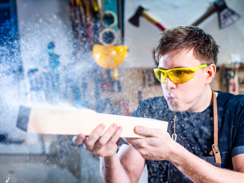 Young carpenter sawing board with circular saw .