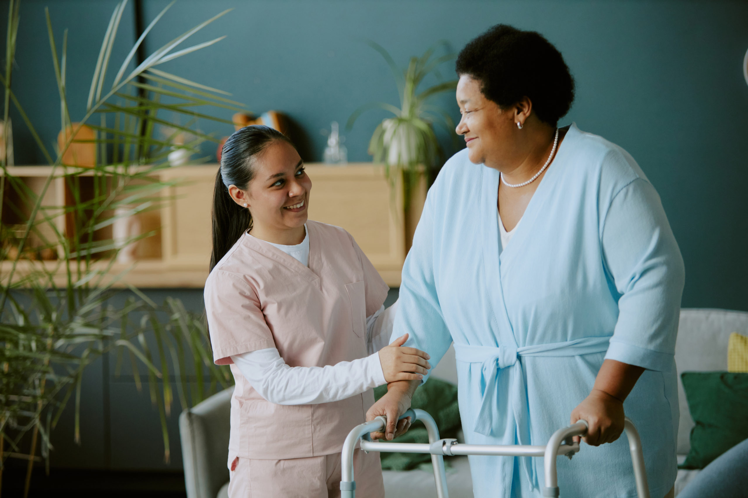 A middle aged woman smiling and holding hands with a elderly woman.