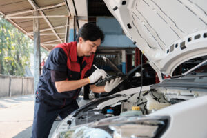Mechanic worker inspects and maintains service of electric engine and battery in automobile garage