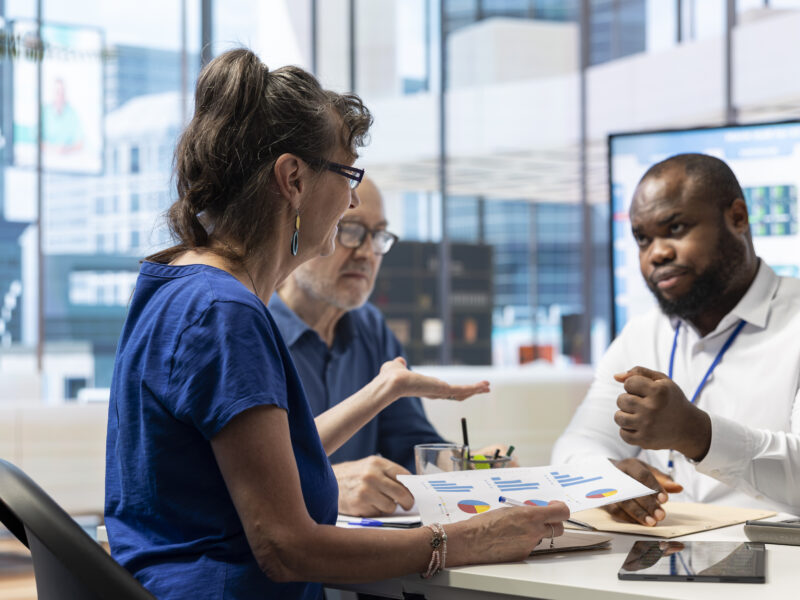 Three people discuss data in an office setting