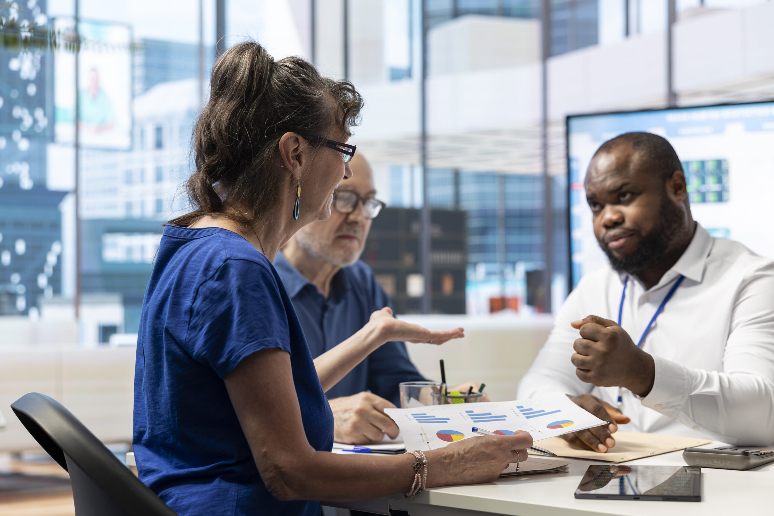 Three people discuss data in an office setting
