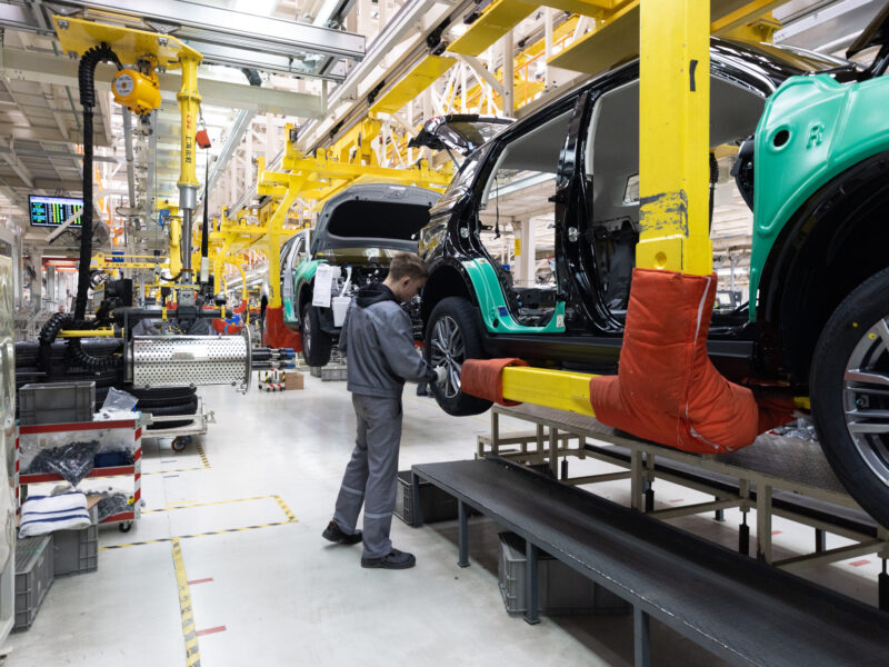 Worker checks a car during factory assembly
