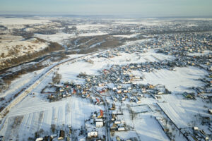 Aerial view of private homes with snow covered roofs in rural suburbs town area in cold winter.