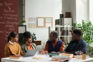 Black professor talking to group of students sitting at table