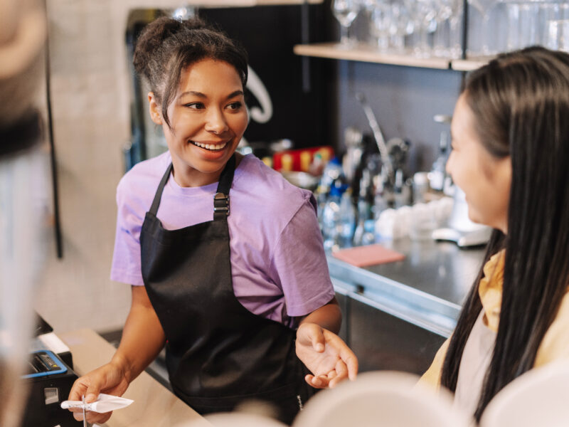 Barista is smiling at a customer while taking an order in a coffee shop