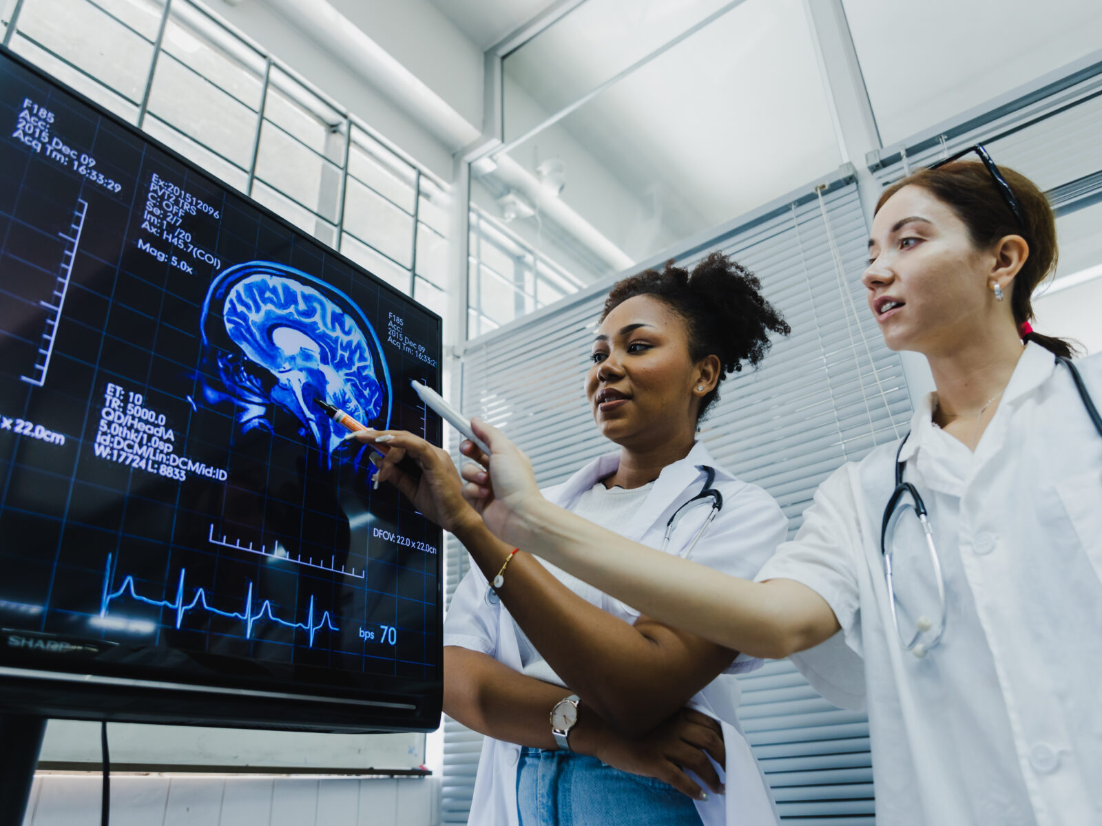Two medical professionals examining a brain scan on a monitor.