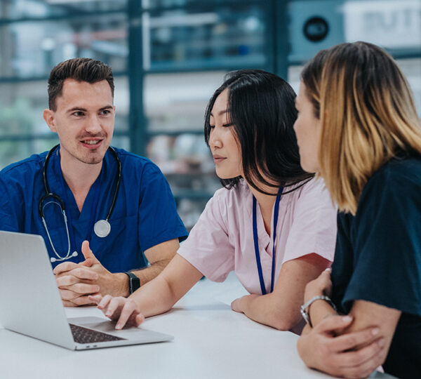 Three healthcare workers having a discussion around a laptop