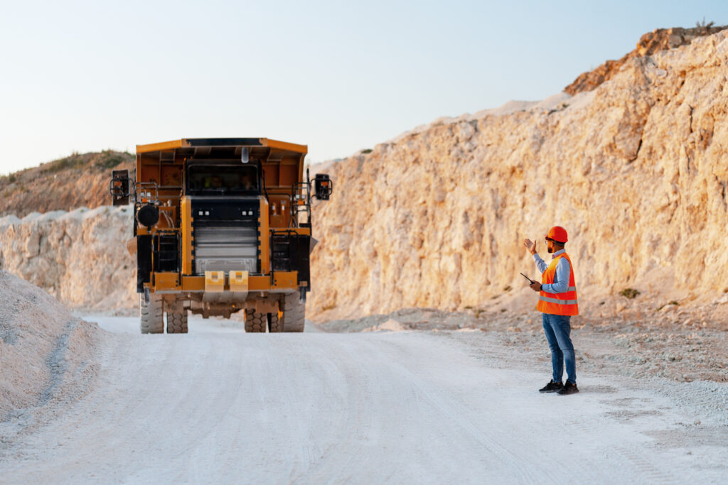 Mining worker directing a large haul truck in an open-pit mine.