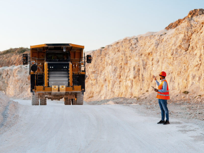 Mining worker directing a large haul truck in an open-pit mine.
