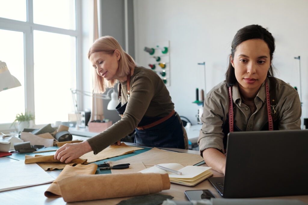 Two women collaborating in a design studio, working with leather and fabric materials