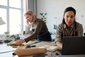 Two women collaborating in a design studio, working with leather and fabric materials