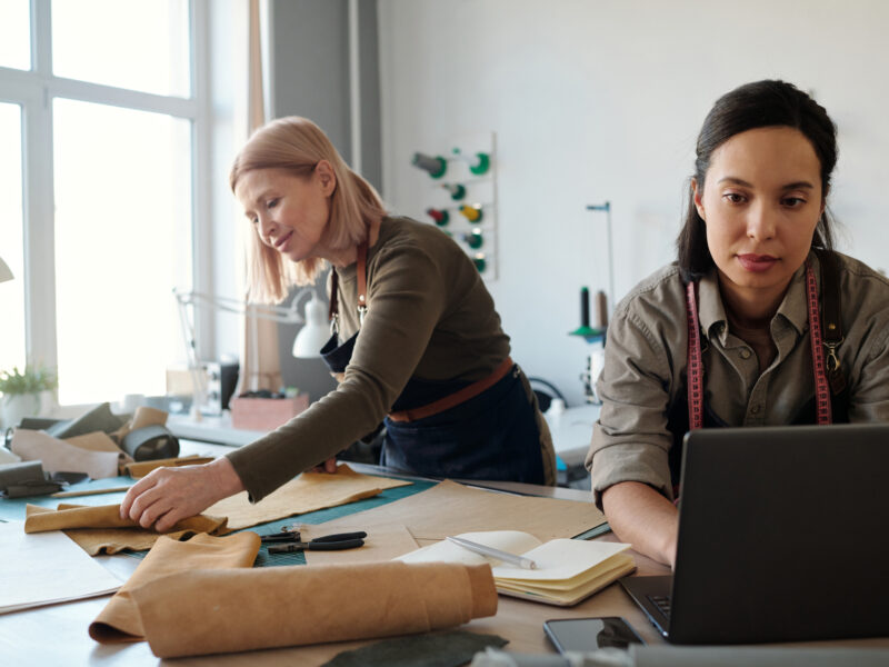 Two women collaborating in a design studio, working with leather and fabric materials