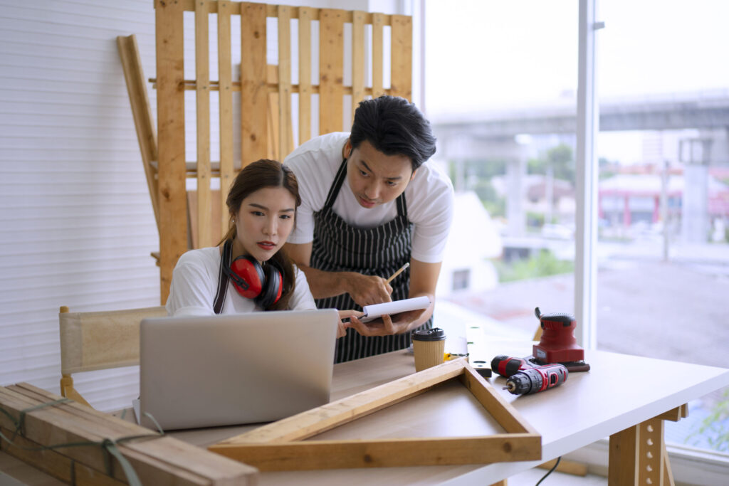 Two carpenters working on a woodworking project together in a bright workshop.