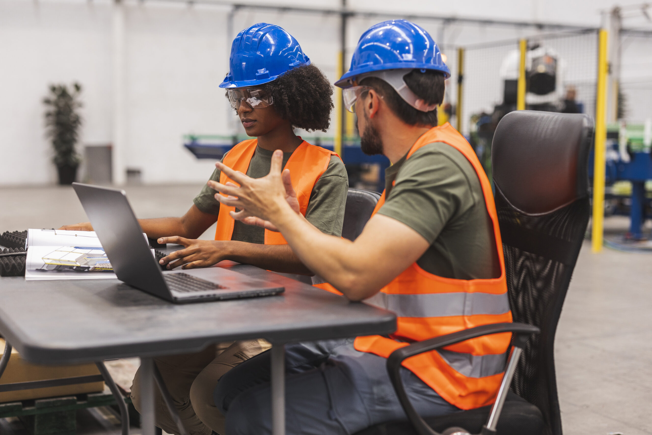Engineers collaborating on laptop in modern factory setting